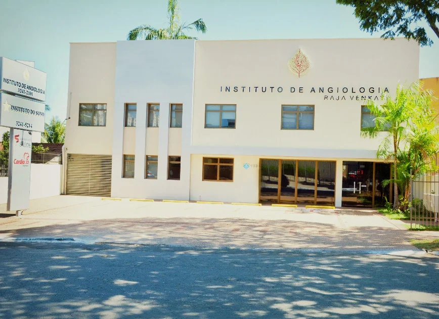 Fachada branca de dois andares do Instituto de Angiologia Raja Venkata, com o letreiro do instituto, numa rua arborizada do Setor Bueno.